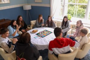 Eine Gruppe Jugendlicher spielt gemeinsam an einem Tisch Gesellschaftsspiele