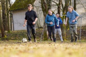 Jungendliche spielen zusammen auf einem Acker Fußball